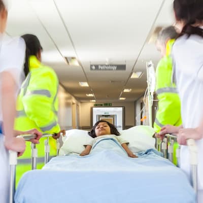 Providers moving patient down hospital hallway.
