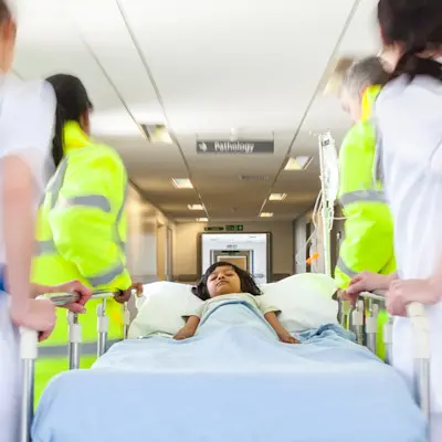 Providers moving patient down hospital hallway.