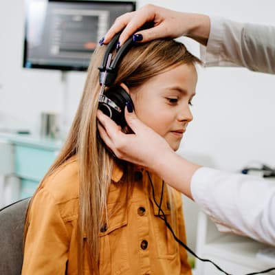 Provider putting headphones on patient's ears.