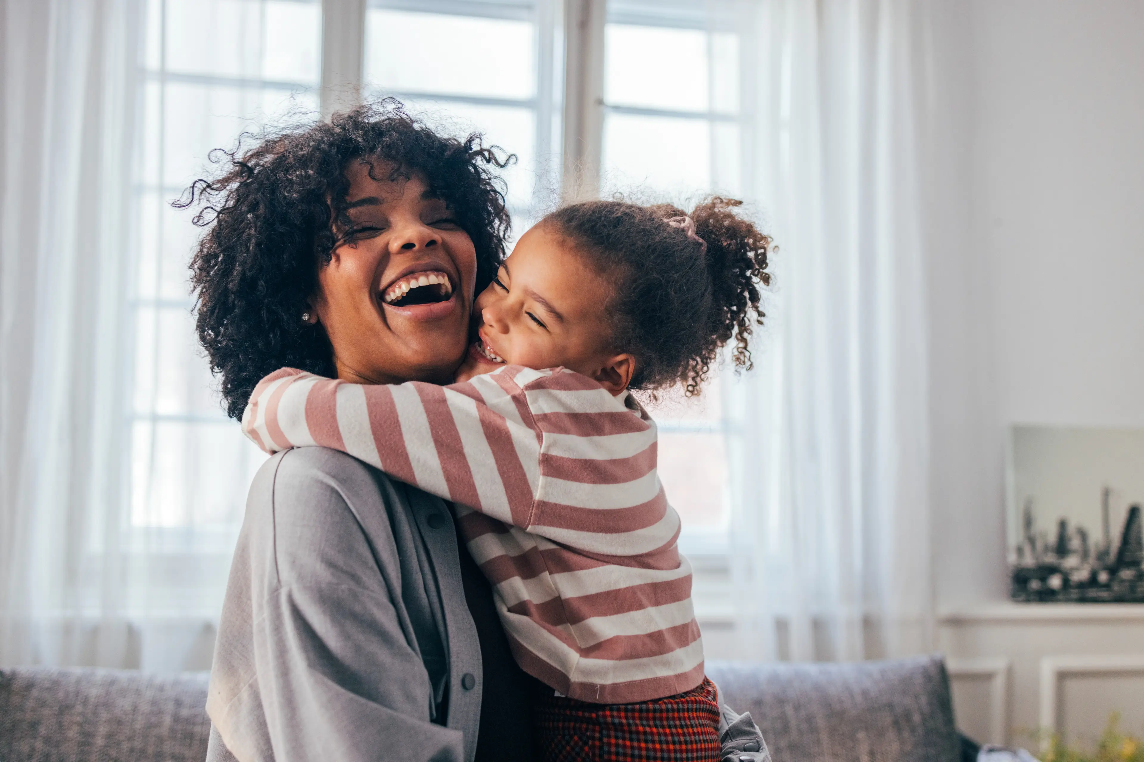 Young girl hugging and laughing with mother.
