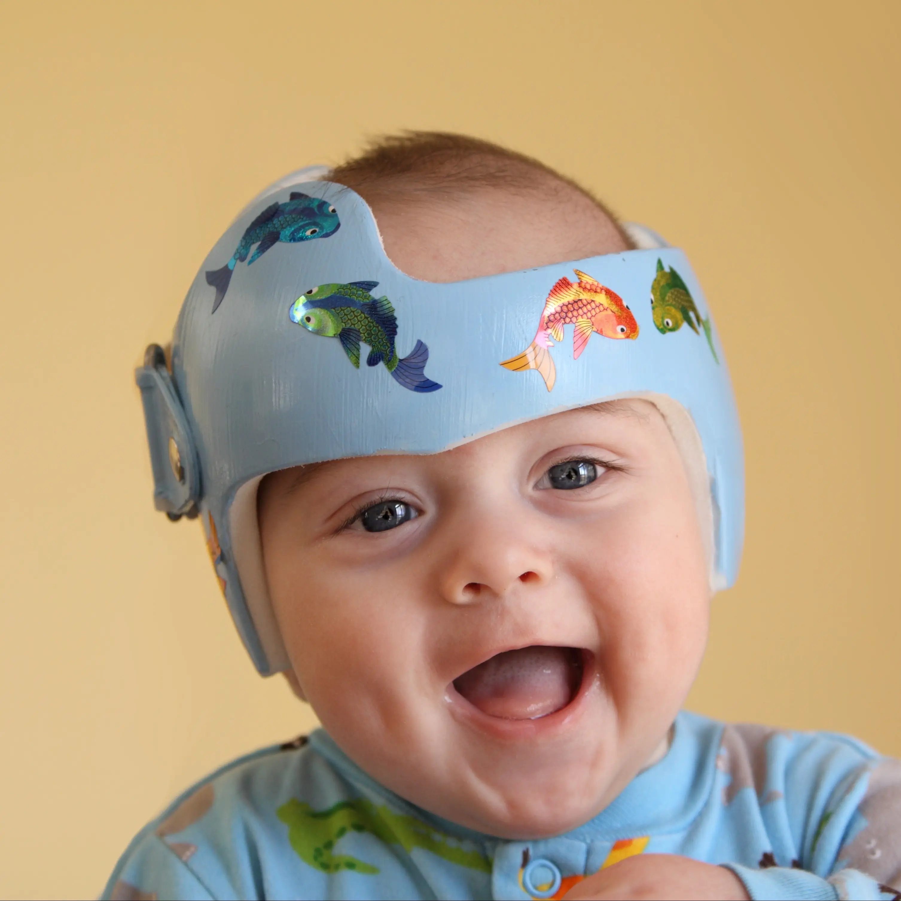 Infant smiling while wearing a helmet.