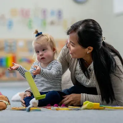 Young child with developmental delays playing with toys in front of pediatric doctor.