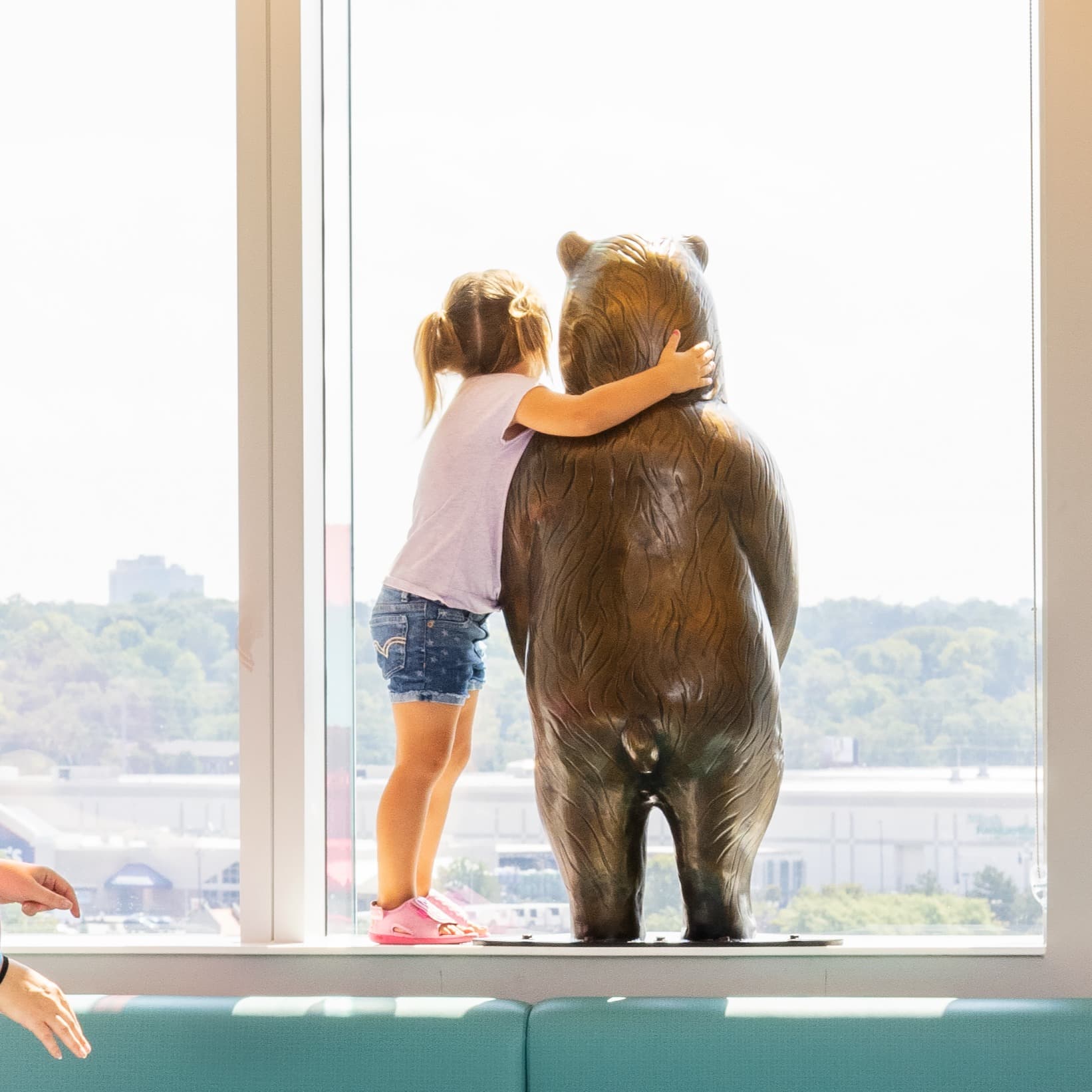 Mother and young patient hugging bear statue at Children's Nebraska.