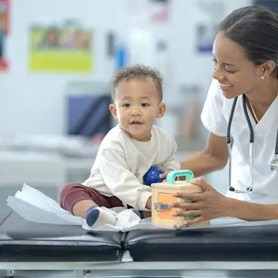 Nursing making baby smile in exam room.