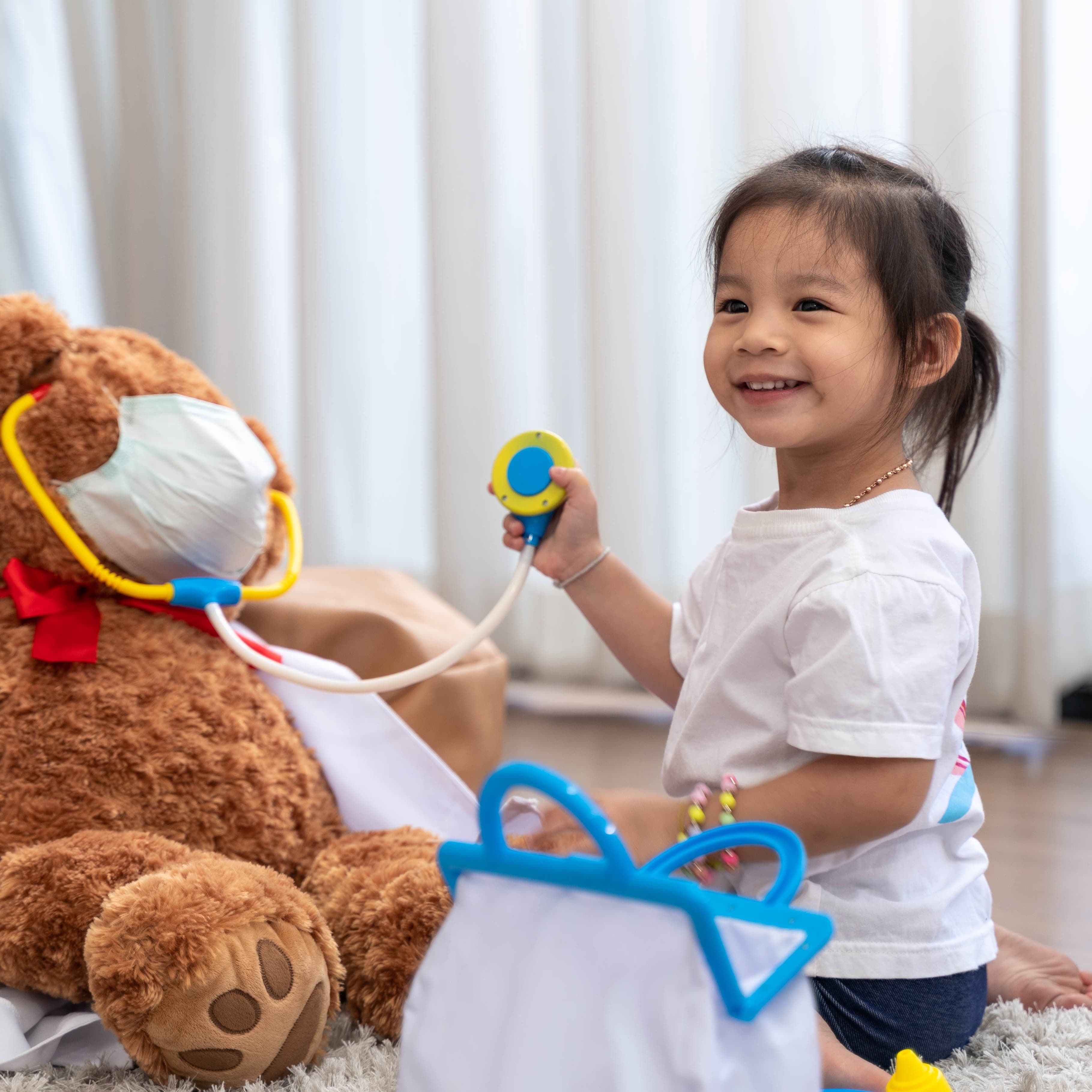 Young child playing doctor with stuffed animal.
