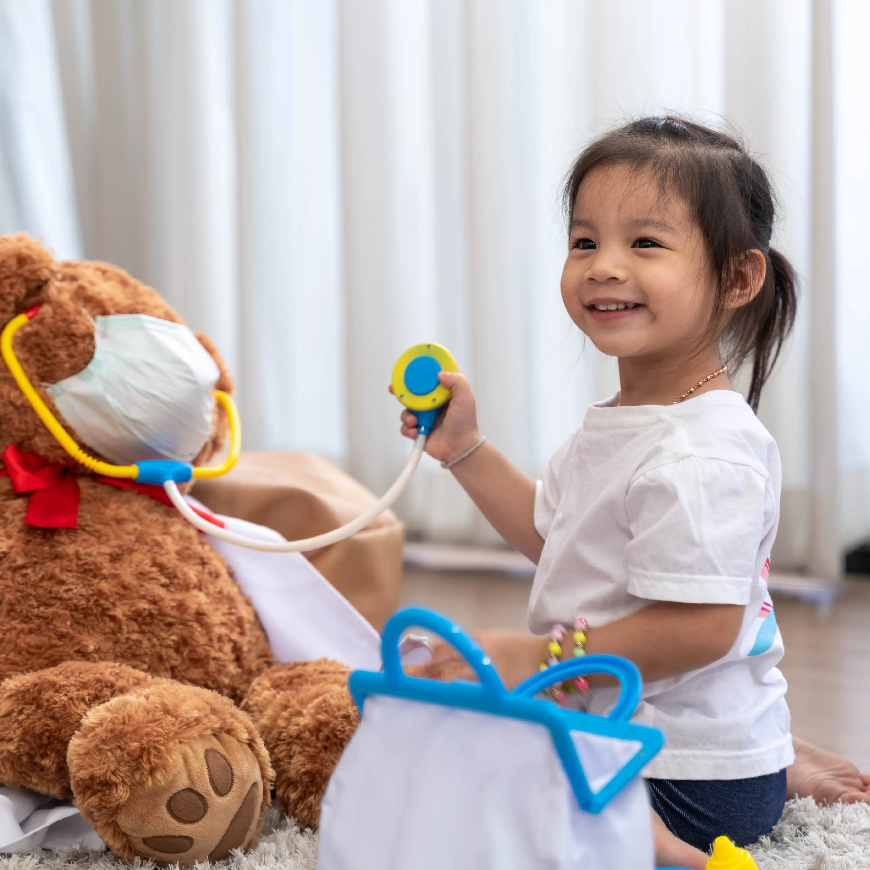 Young child playing doctor with stuffed animal.