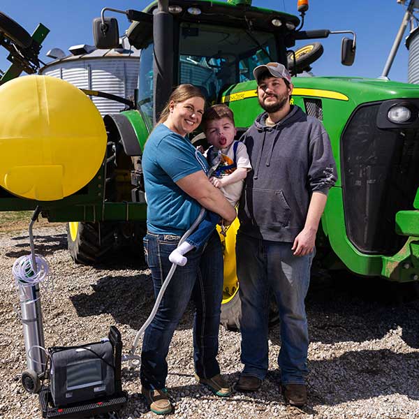 Friesen family standing in front of a tractor on a farm.