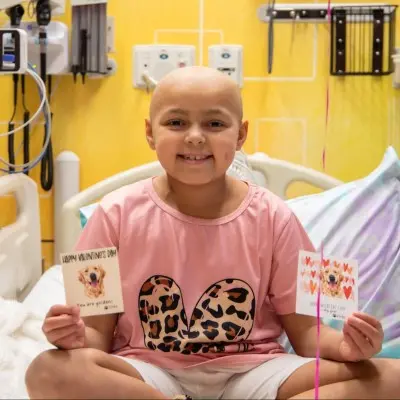 Young patient at Children's Nebraska holding two cards.
