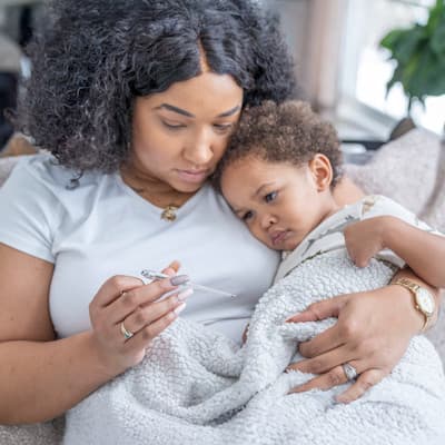 Mother checking sick baby's temperature.