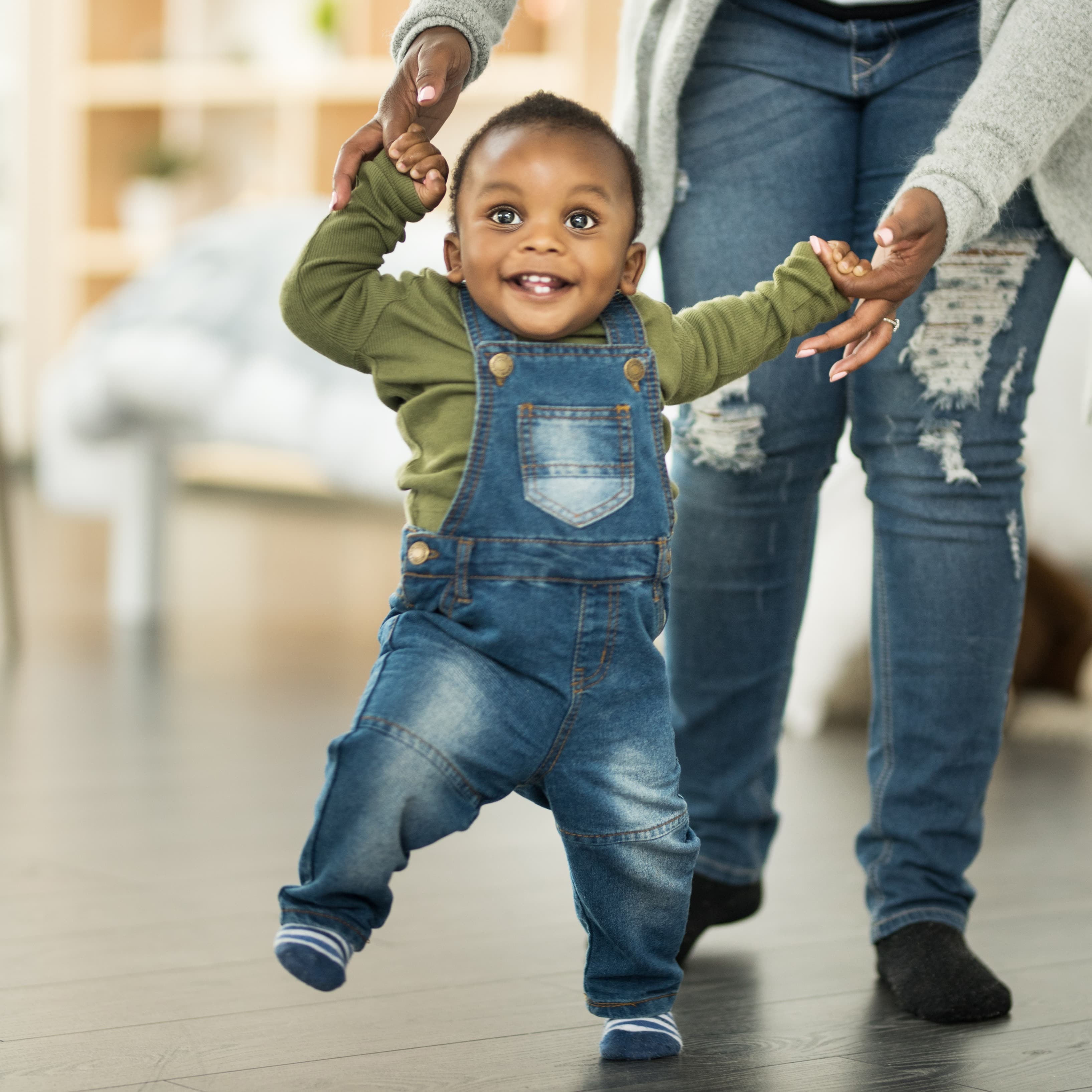 Mom helping her toddler son walk.