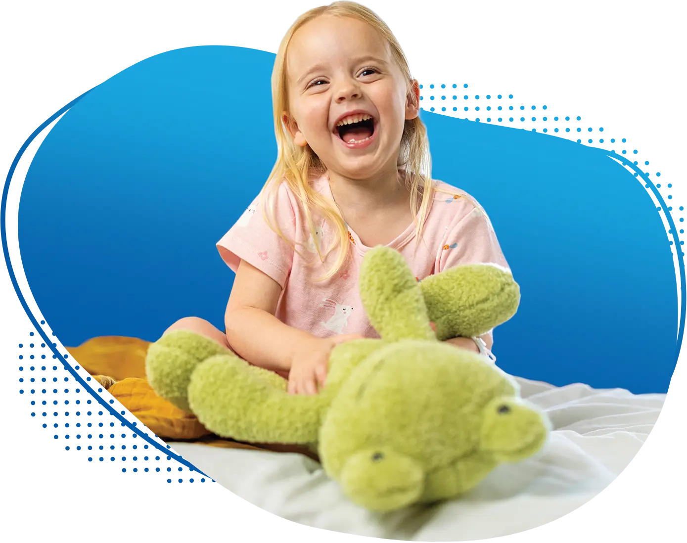 Smiling young female pediatric patient holding a stuffed animal frog toy while sitting on her hospital bed at Children's Nebraska.