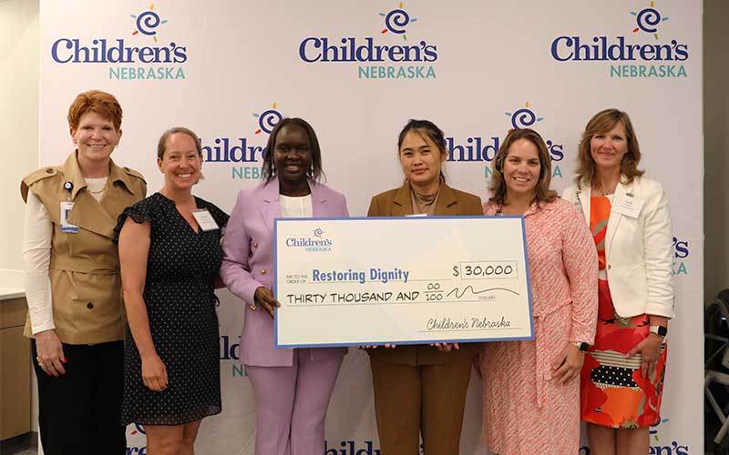 Restoring Dignity and Children's Nebraska representatives hold a large check for $30,000.