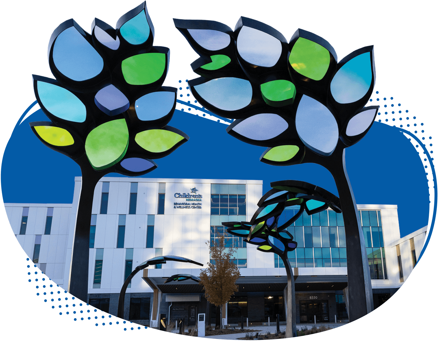 A view of the sidewalk and stained glass tree sculptures leading to the front door of the new Behavioral Health and Wellness Center at Children's Nebraska.