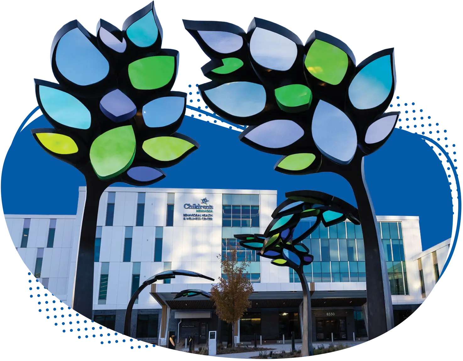 A view of the sidewalk and stained glass tree sculptures leading to the front door of the new Behavioral Health and Wellness Center at Children's Nebraska.