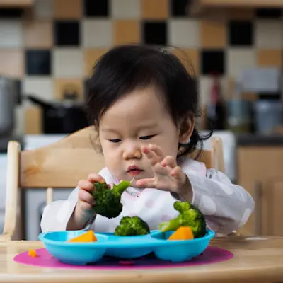Toddler girl eating vegetables.