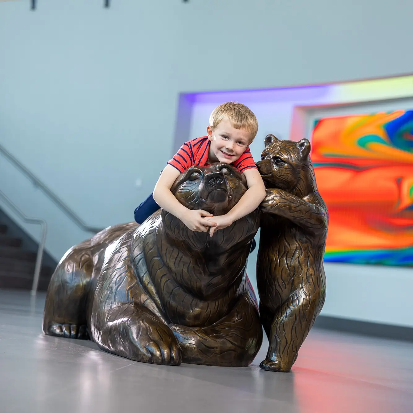 Young patient hugging bear in hospital lobby.