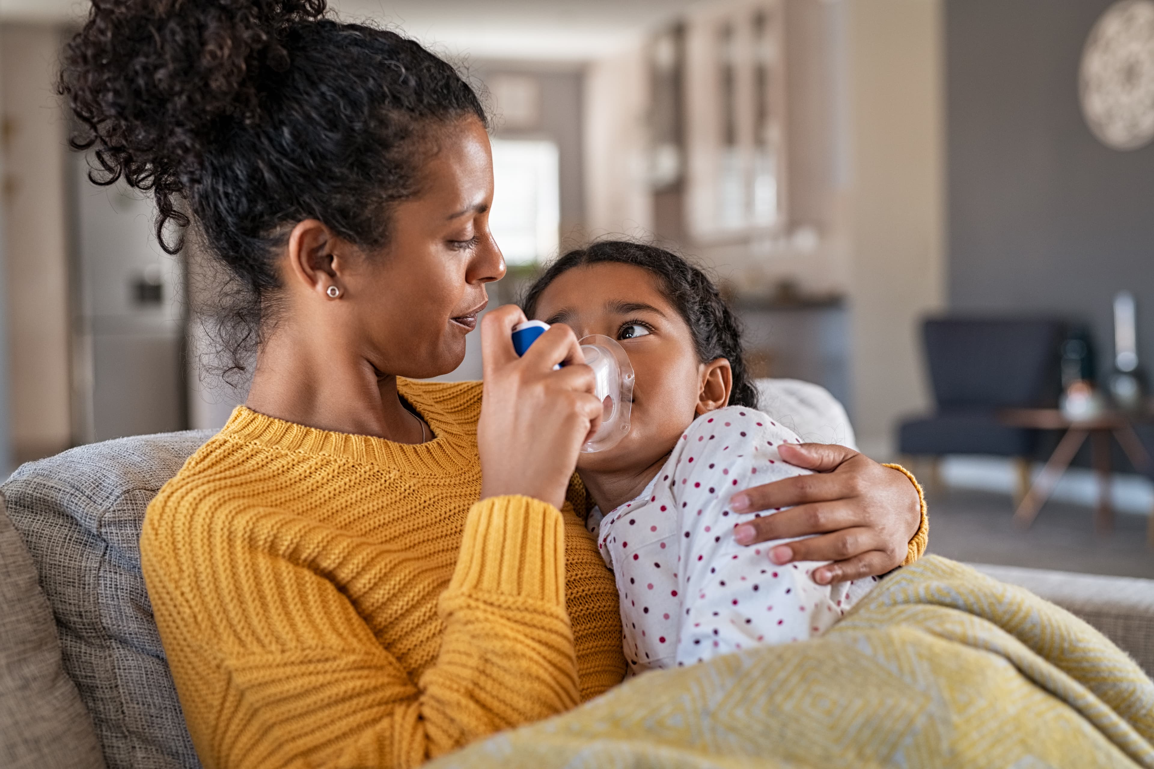 Mother holding child giving her a breathing treatment.