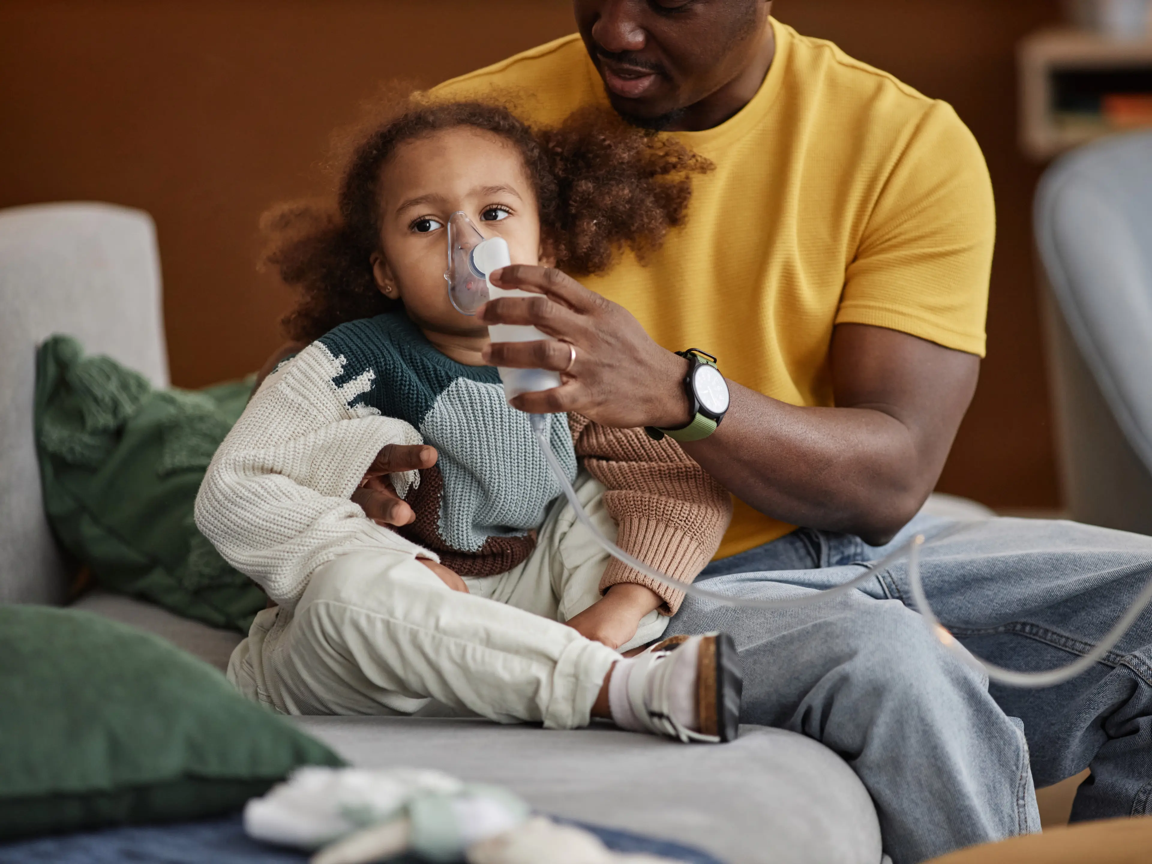 Young girl getting asthma treatment from father.