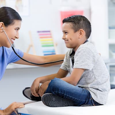 Provider listening to young boy's lungs.