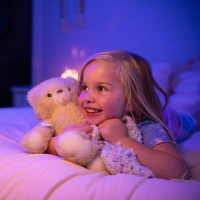 Young girl holding teddy bear looking off in the distance.