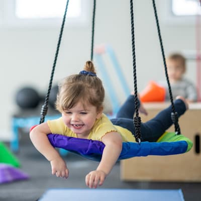 Girl laying on therapy swing.