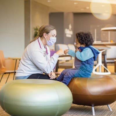 Children's provider fist-bumping young patient in the Children's Nebraska hospital lobby