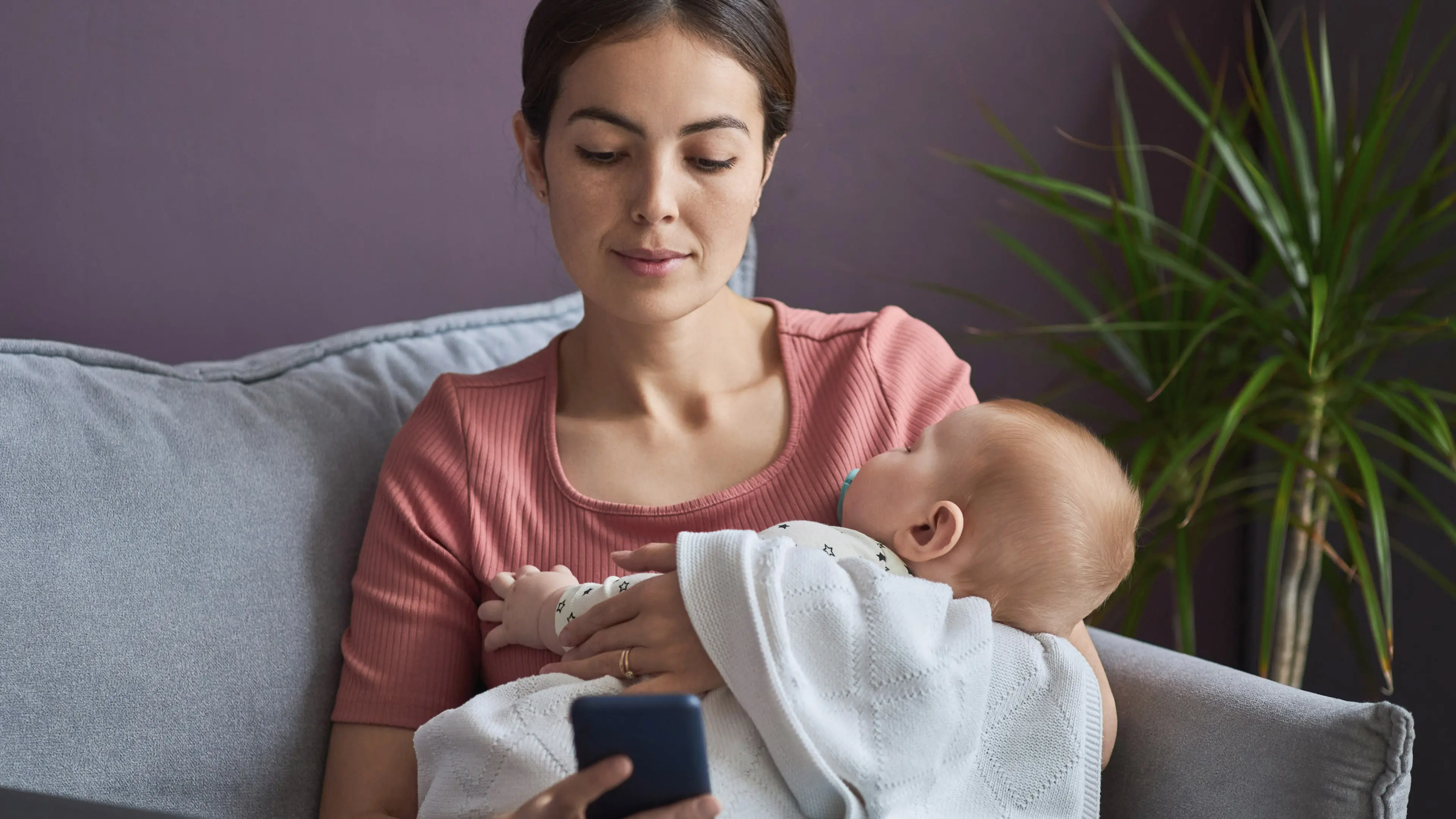 Parent researching while holding child.