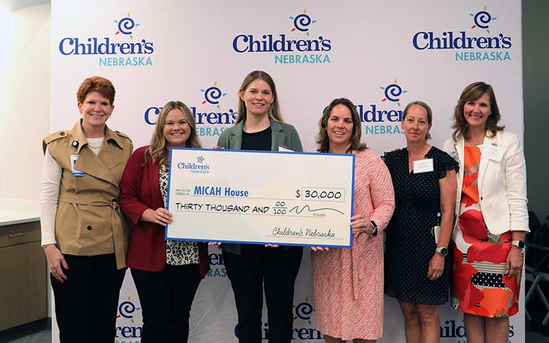 Micah House and Children's Nebraska representatives hold a large check for $30,000.