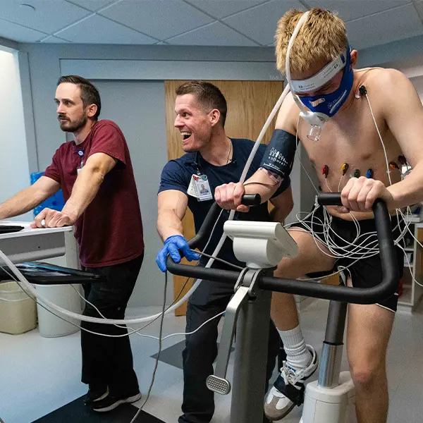 Medical professionals monitoring an athlete wearing oxygen mask and monitoring equipment during fitness test.