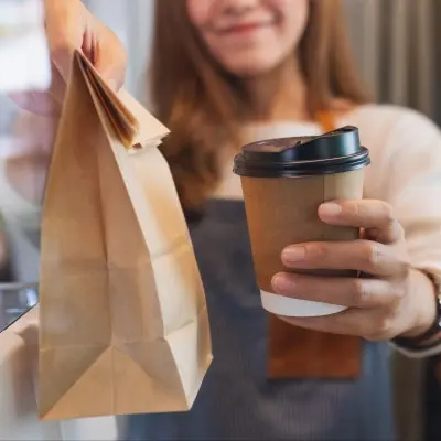 Barista handing parent a coffee and a meal.
