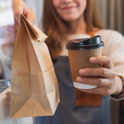 Barista handing parent a coffee and a meal.
