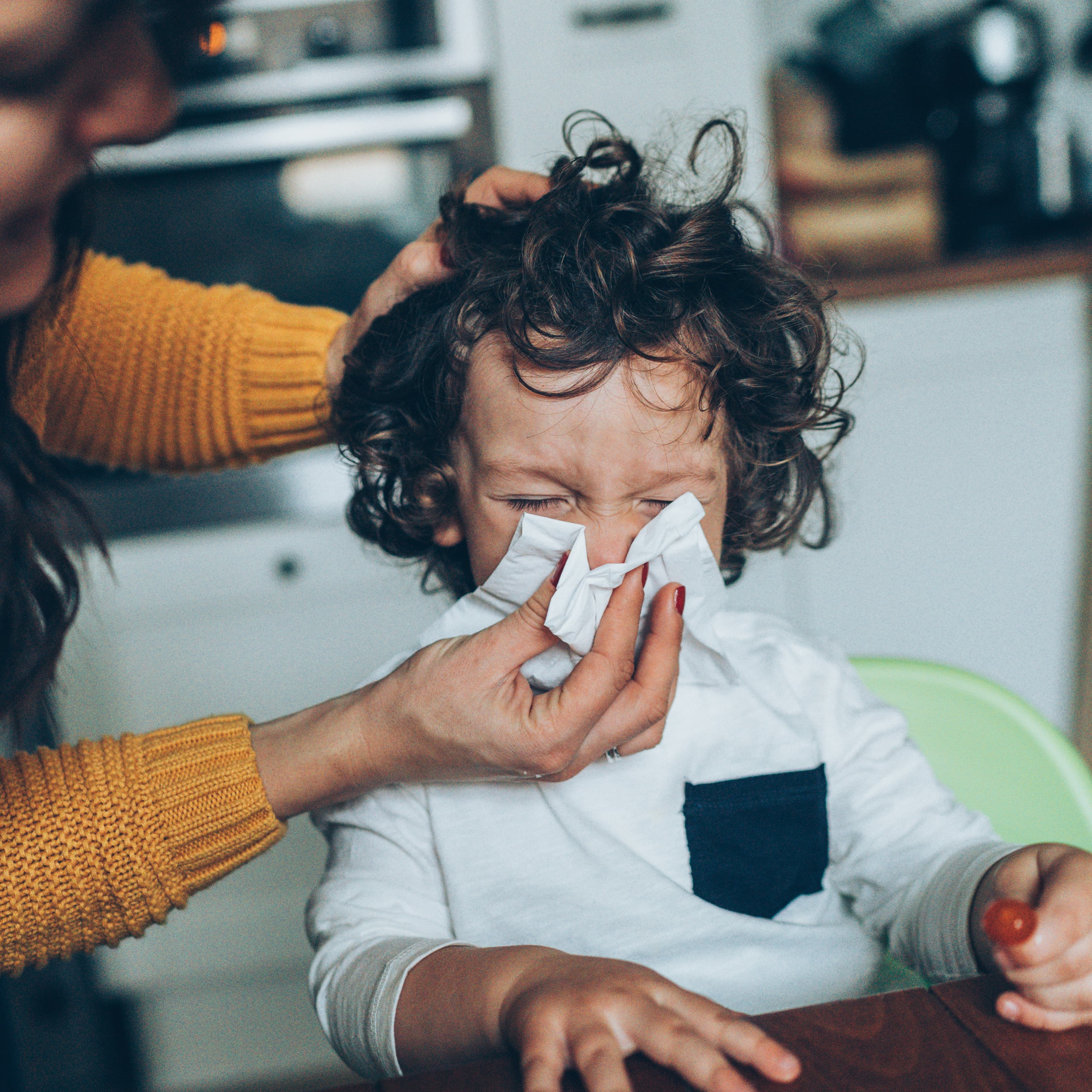 Young boy blowing his nose.