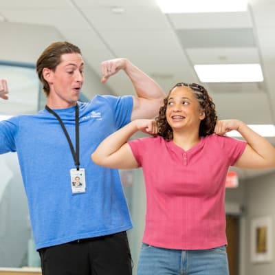 Children's Nebraska provider flexing muscles and laughing playfully with teenage patient.