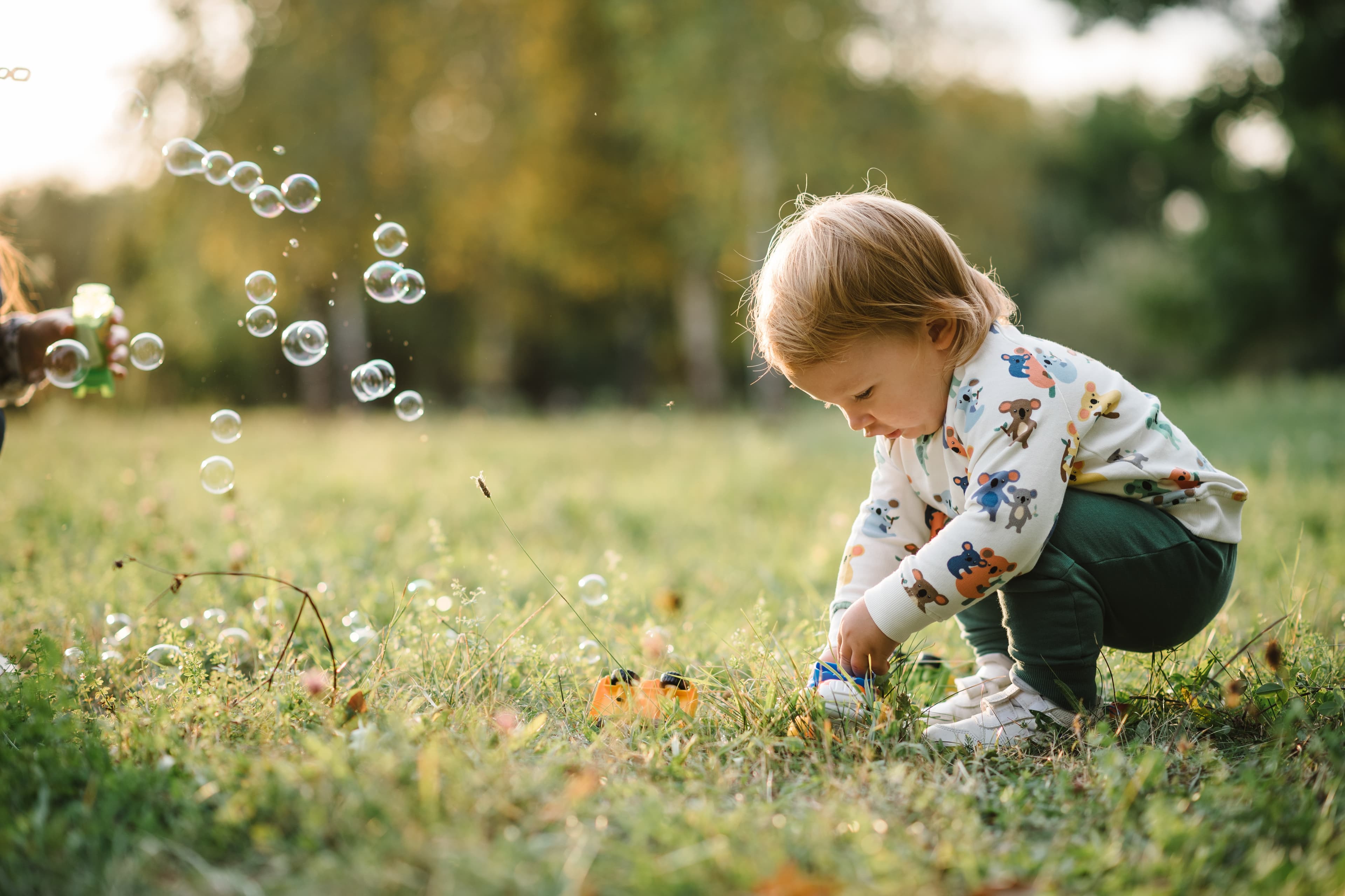 Young child playing outside with bubbles.