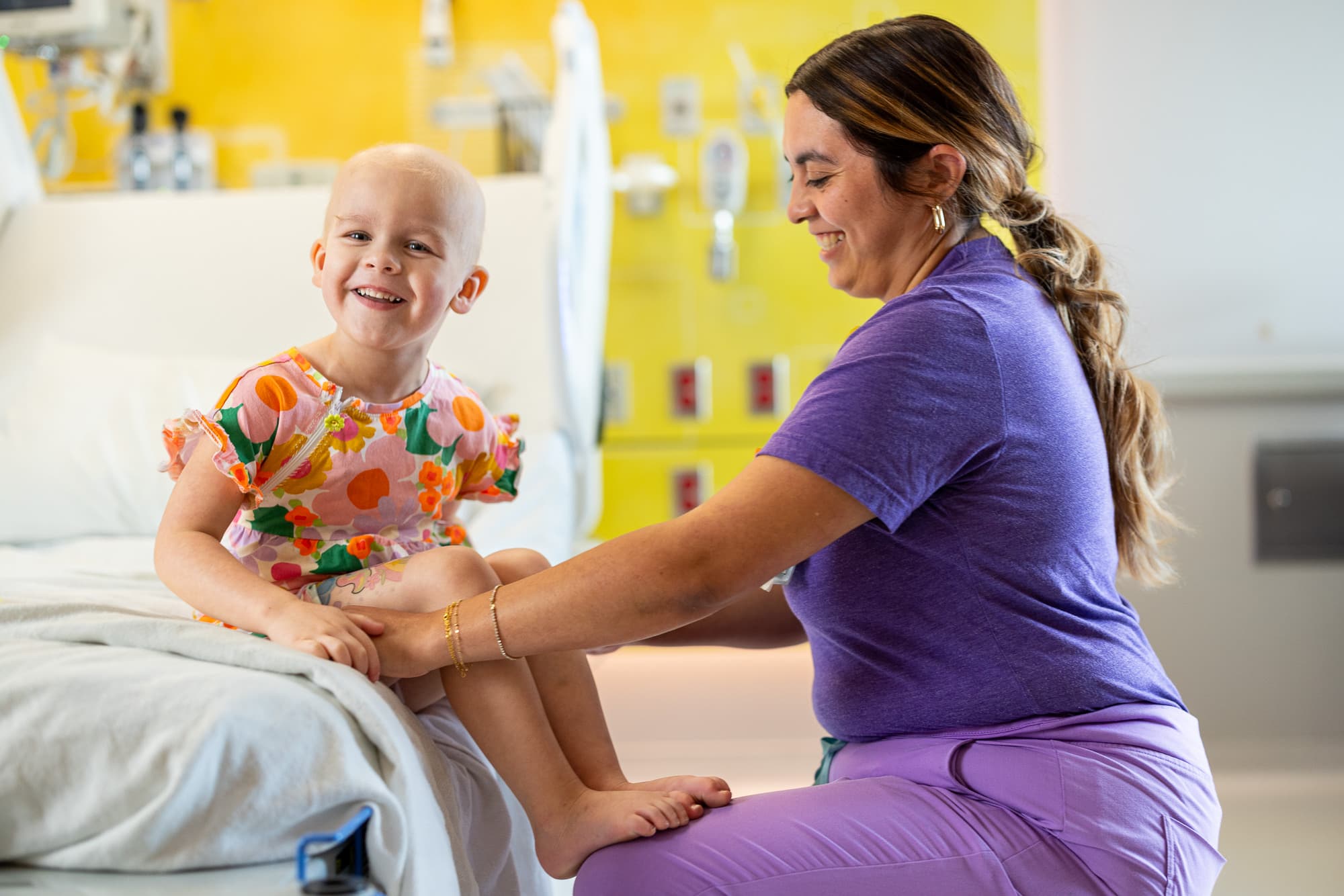 nurse wearing a purple shirt with a young child wearing a colorful dress