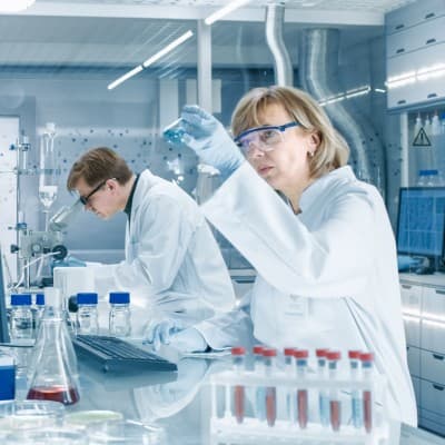Medical researcher observing beaker in a lab.
