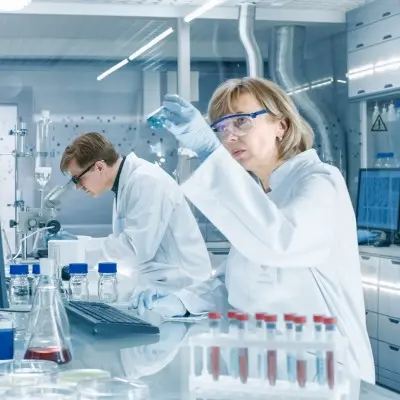 Medical researcher observing beaker in a lab.