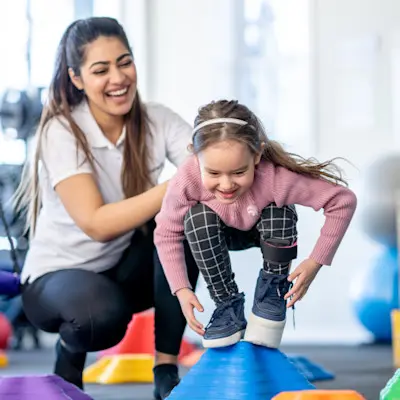 Provider helping girl with therapy exercise.