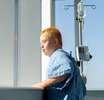 Young male patient hopefully gazing out the window of his inpatient hospital room while at Children's Nebraska.