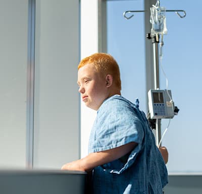 Young male patient hopefully gazing out the window of his inpatient hospital room while at Children's Nebraska.