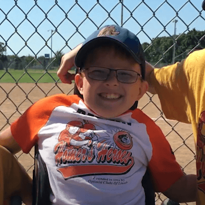 Dathin smiling with his siblings and friends on the baseball field.