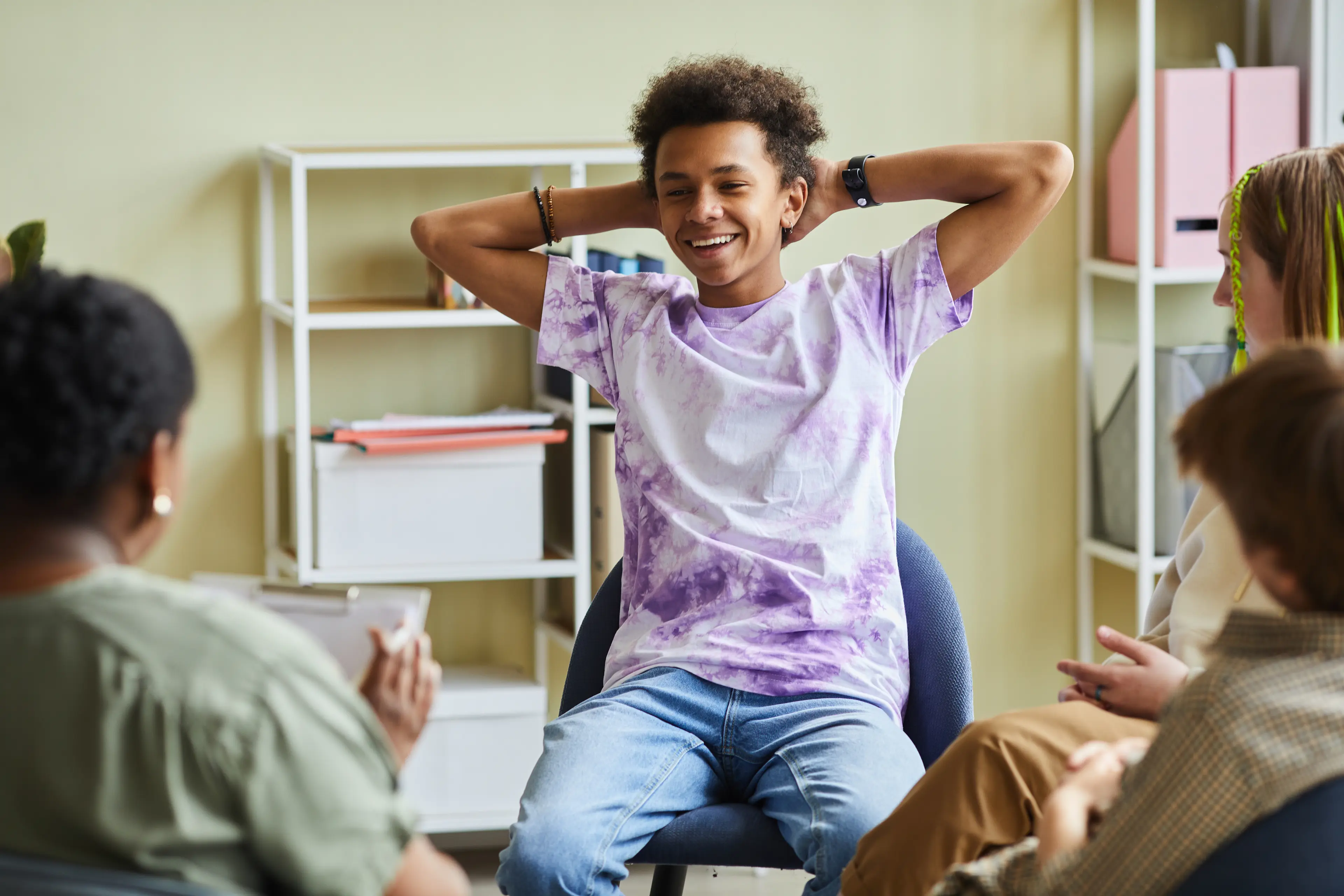 youth boy in group therapy session, smiling, wearing a purple shirt