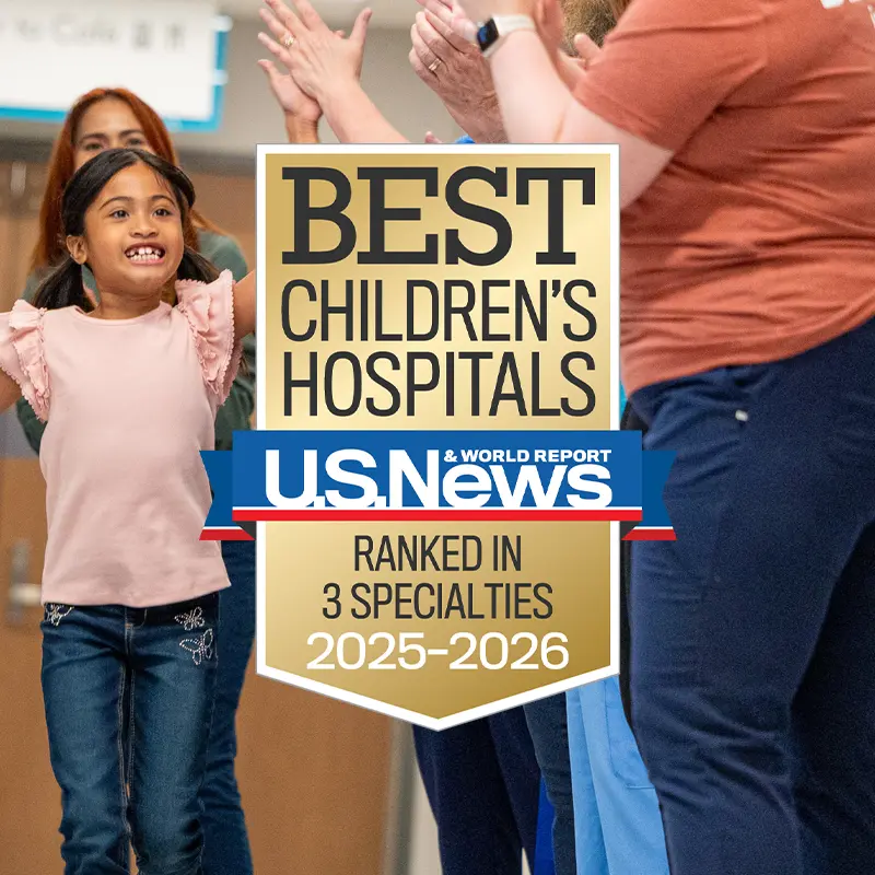 Young patient high-fiving nurses with Children's Nebraska U.S. News & World Report Ranked in 3 Specialties badge.