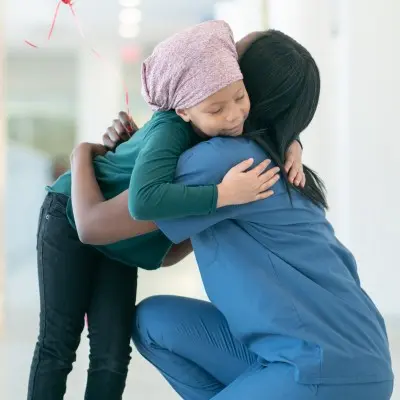 Nurse hugging young patient in hospital.