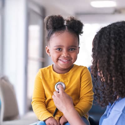 Provider listening to young patient's heart.