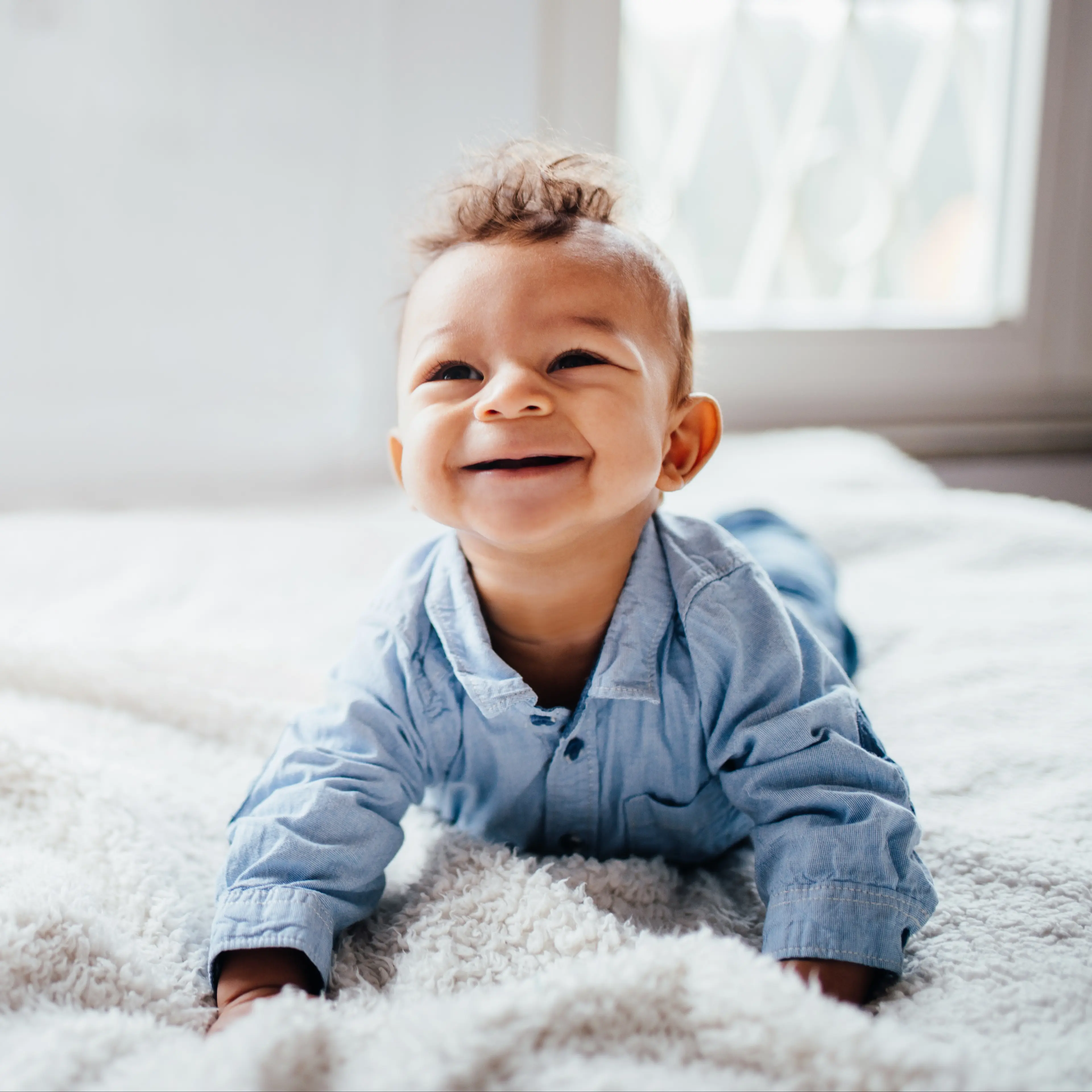 Infant boy smiling during tummy time.