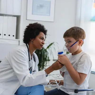 Provider giving breathing treatment to child.