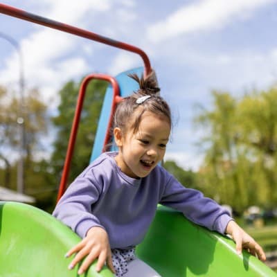 Young child going down the slide at a playground.