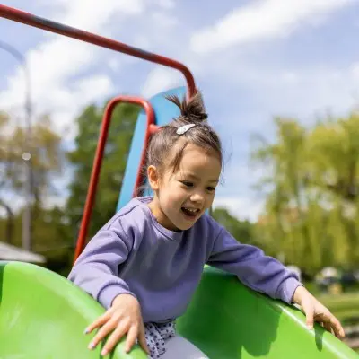 Young child going down the slide at a playground.