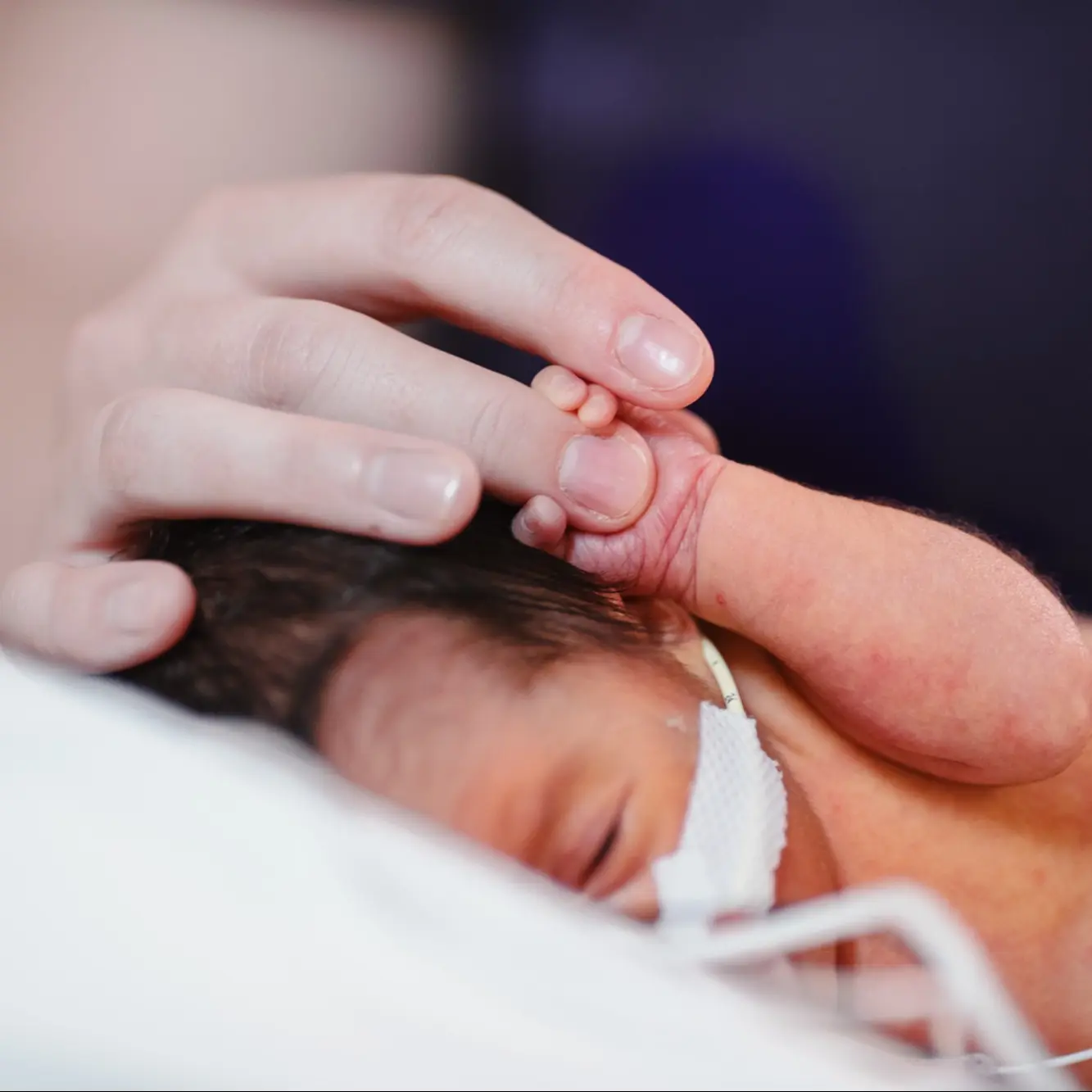Children's provider holding infant's hand in the hospital.
